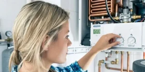 Woman in plaid shirt inspecting furnace unit checking for dusty or burning smell from HVAC system