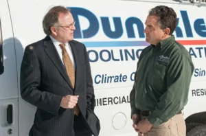 Connecticut State Senator Andrew Maynard meeting with Jonathan Duncklee owner of Duncklee Cooling and Heating beside company van in Stonington Connecticut