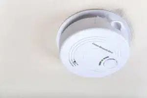 White circular carbon monoxide alarm detector mounted on ceiling for home safety against CO poisoning