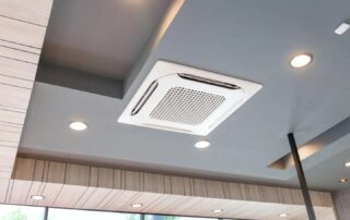 White ceiling cassette air conditioning unit installed in modern interior with wood panel ceiling recessed lighting and large windows for optimal indoor air quality and ventilation