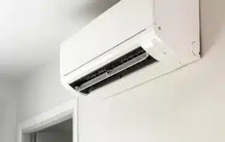 white ductless mini-split indoor unit mounted high on a living room wall